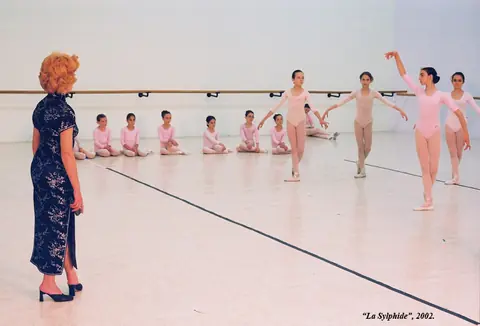 Pedagog vodi čas devojčicama u roze trikoima u sali