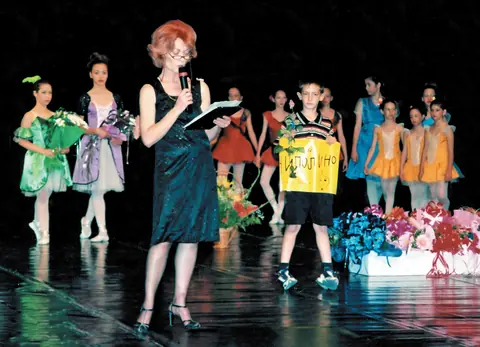 Dobrila Novkov govori na sceni, oko nje učenice u kostimima